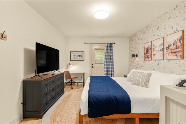 Lower level bedroom equipped with closet, dresser, 50" Roku TV, and private workspace. 