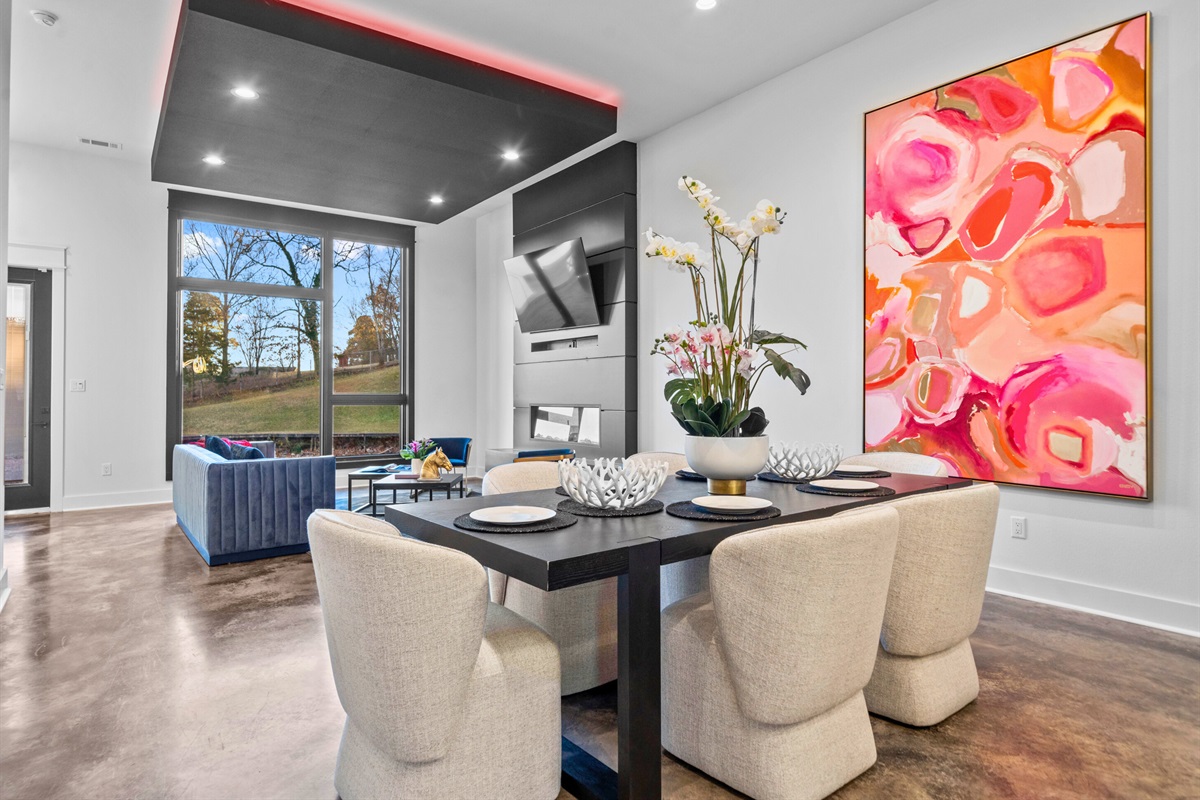 A closer look at this stunning dining setup reveals soft curves, modern furnishings, and vibrant accents that bring the space to life.