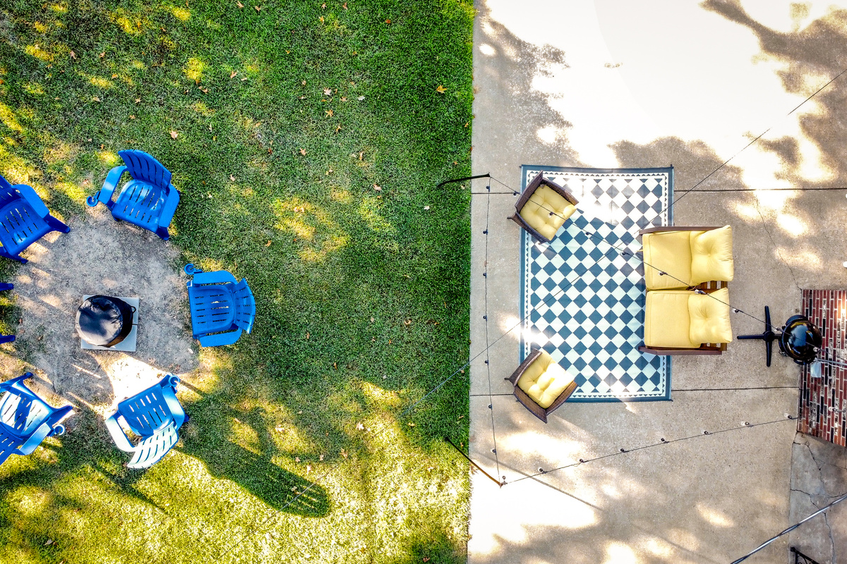 Fenced backyard with string-lit patio, fire pit, and electric grill.
