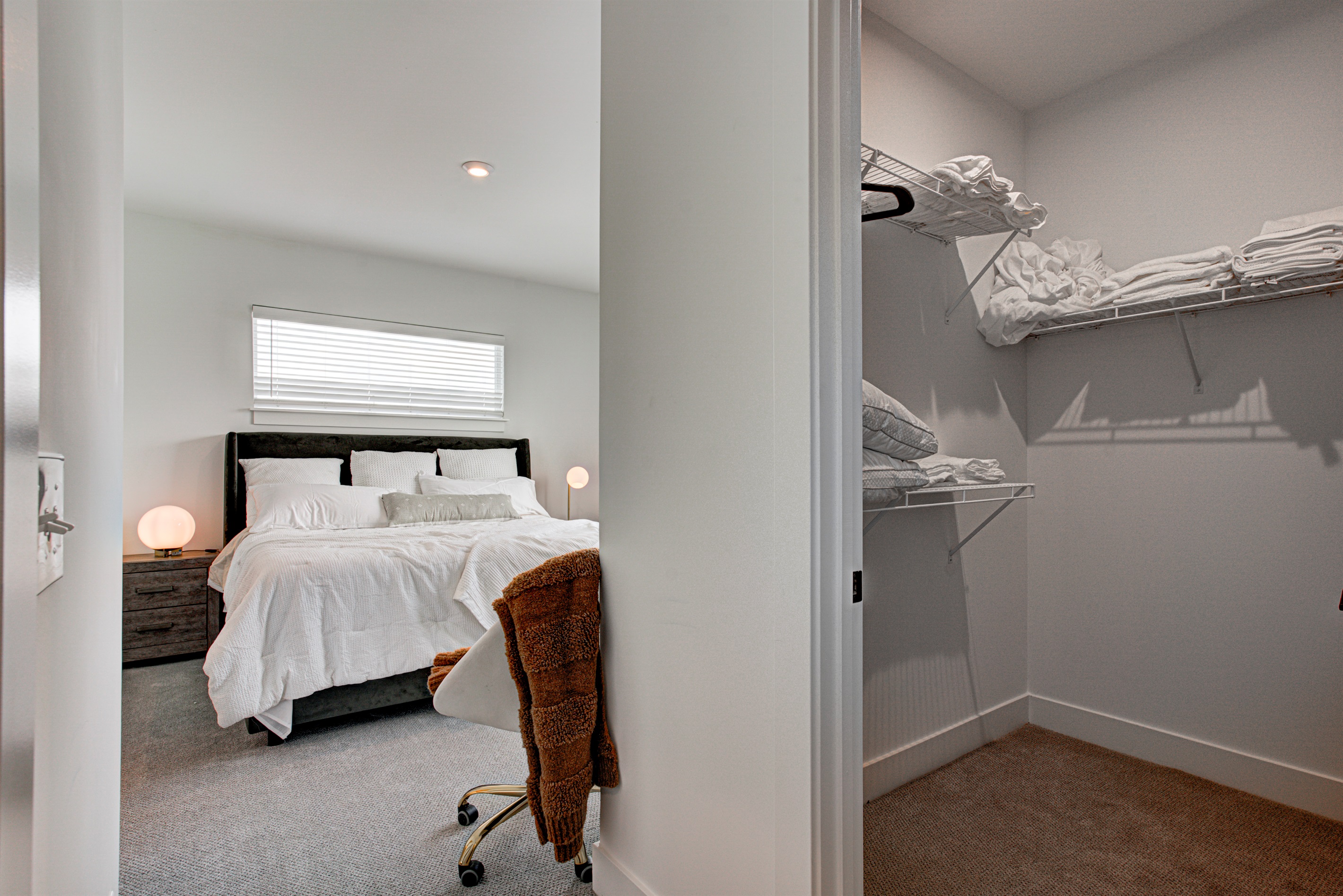 Relax in the serene master bedroom featuring a comfortable king-size bed, soft linens, and cozy pillows. Includes nightstands, lamps, walk-in closet, and full-length mirror for added comfort. 