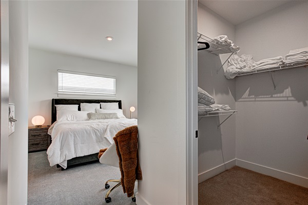 Relax in the serene master bedroom featuring a comfortable king-size bed, soft linens, and cozy pillows. Includes nightstands, lamps, walk-in closet, and full-length mirror for added comfort. 
