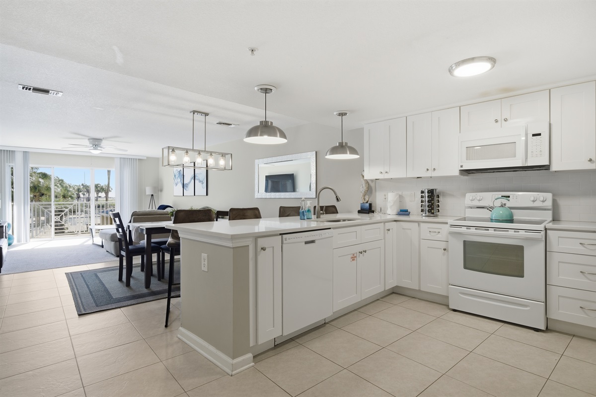 Cook with ease in the fully equipped kitchen featuring bright white cabinetry, ample counter space, and bar seating.