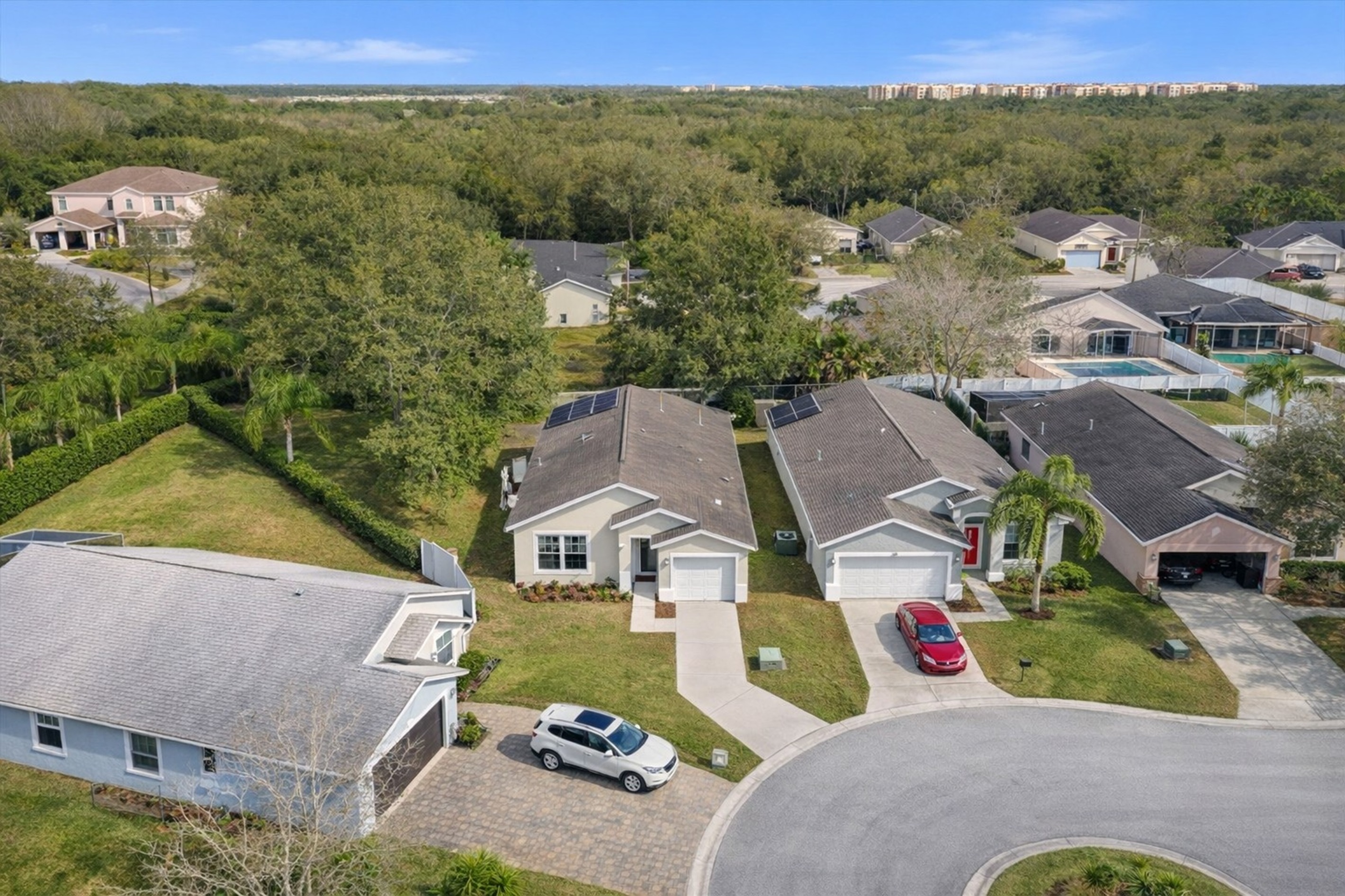 A single-story home with a driveway in a quiet cul-de-sac surrounded by greenery.