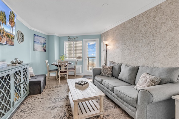 Open living area with plush seating, coffee table, and ocean-inspired décor — steps from the balcony
