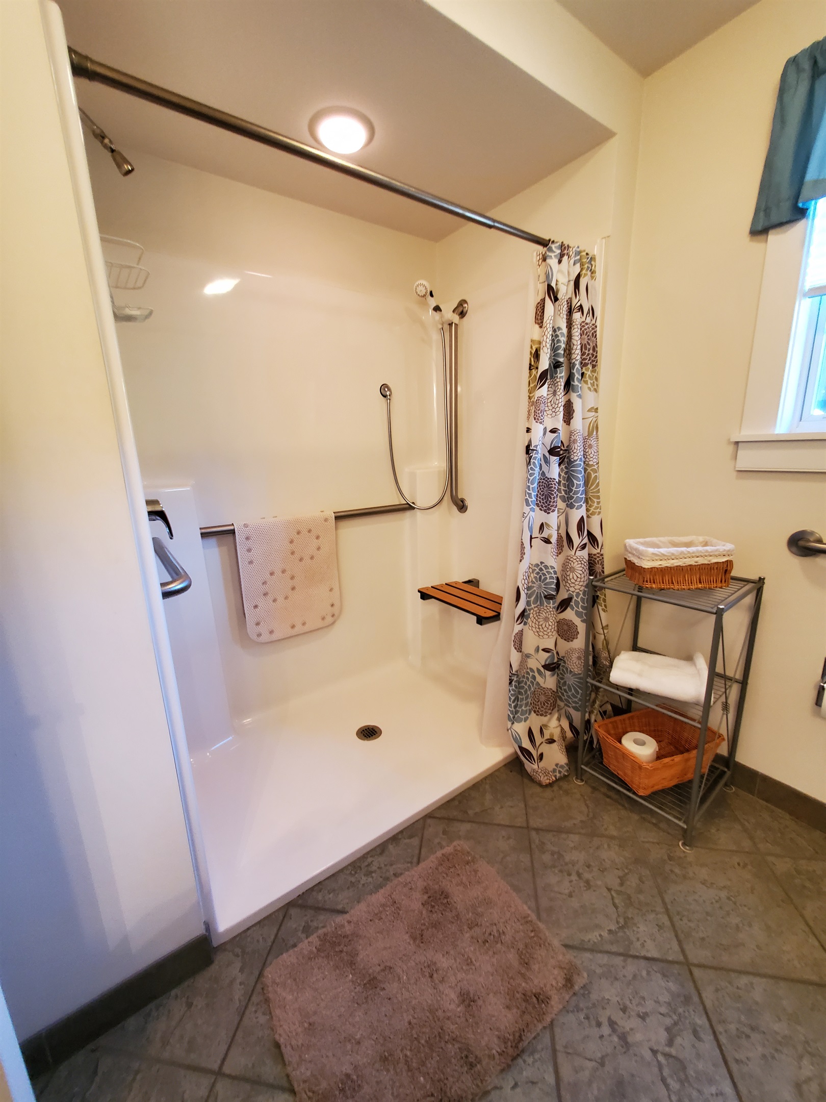Handicap accessible bathroom with shower seat and handheld shower.