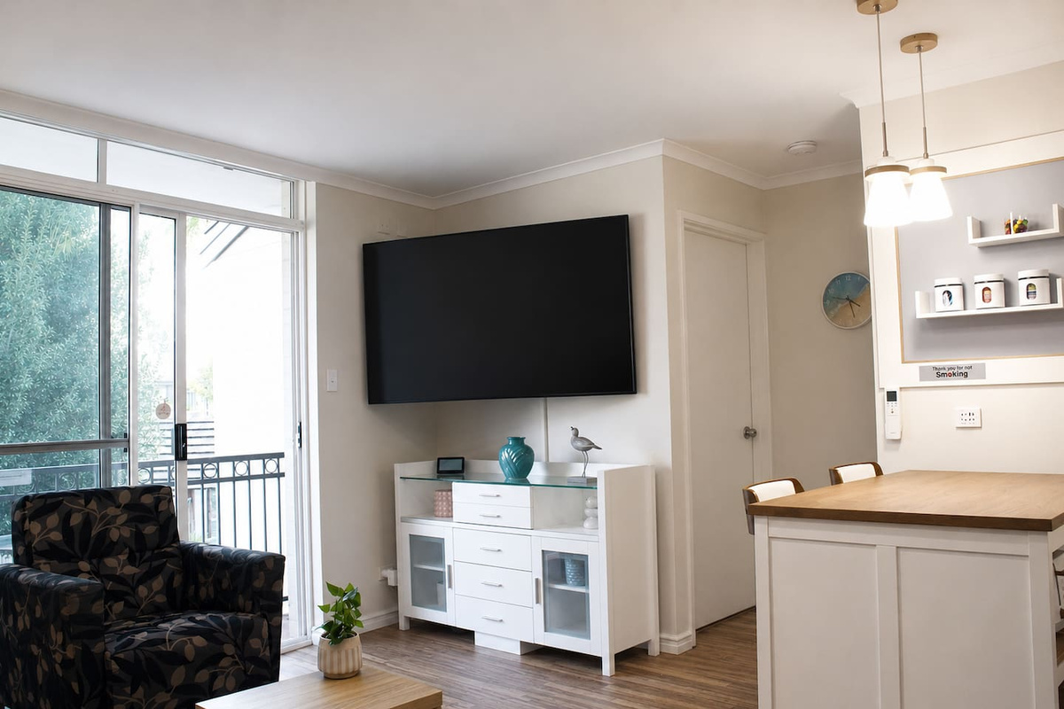 The lounge opens toward the balcony, bringing fresh air and leafy outlooks into the main living space at Sea Breeze Apartment Mandurah.