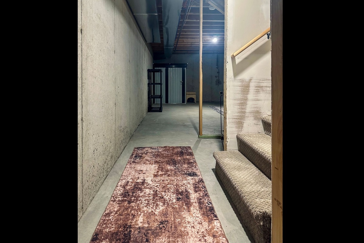 Spacious basement landing leading toward the west storage area, providing practical overflow space that keeps main living areas uncluttered.