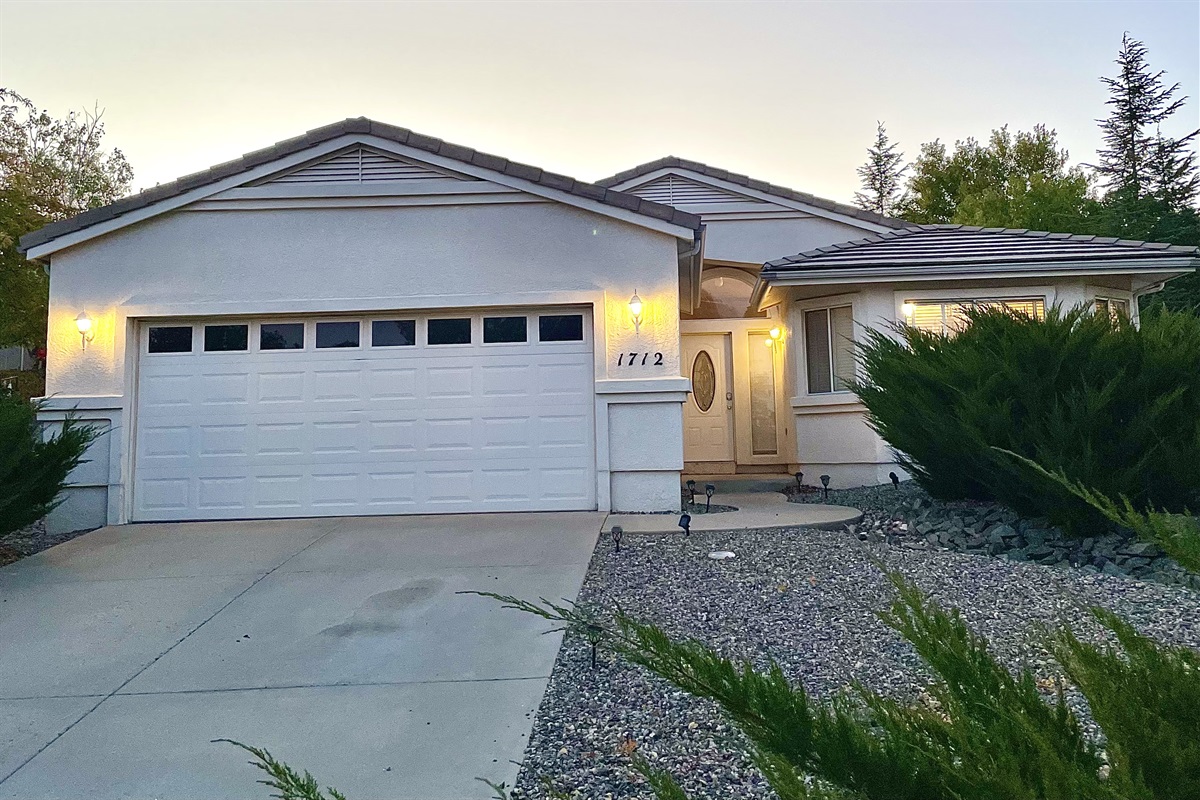 The exterior of the home exudes a sense of welcome and belonging. The well-lit driveway and garage entrance provide a convenient and safe arrival experience