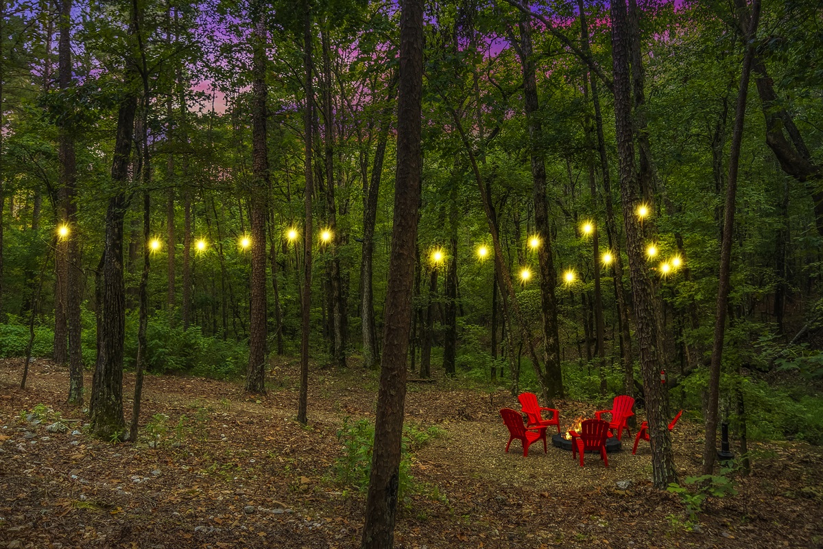 Firepit area and path are lit up by string lights. Firepit area is down by the creek.