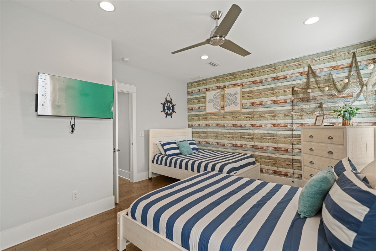 Double Queen Suite with wall-mounted TV and ample space for guests.