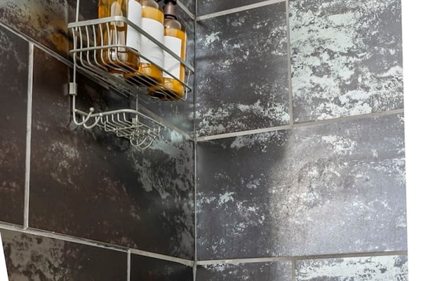 Close-up of the shower area featuring built-in storage rack and provided bath essentials.