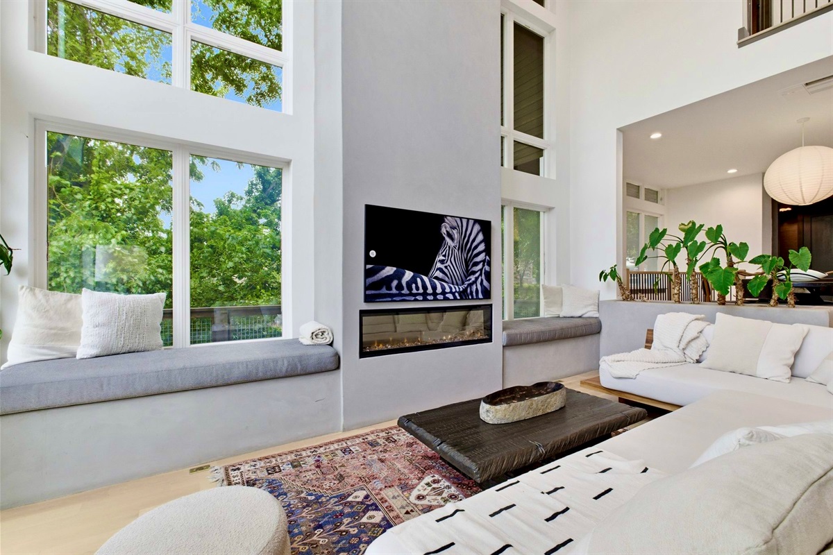 Bright living space w/ a fireplace, plush sofa & warm layered textures for effortless unwinding.
