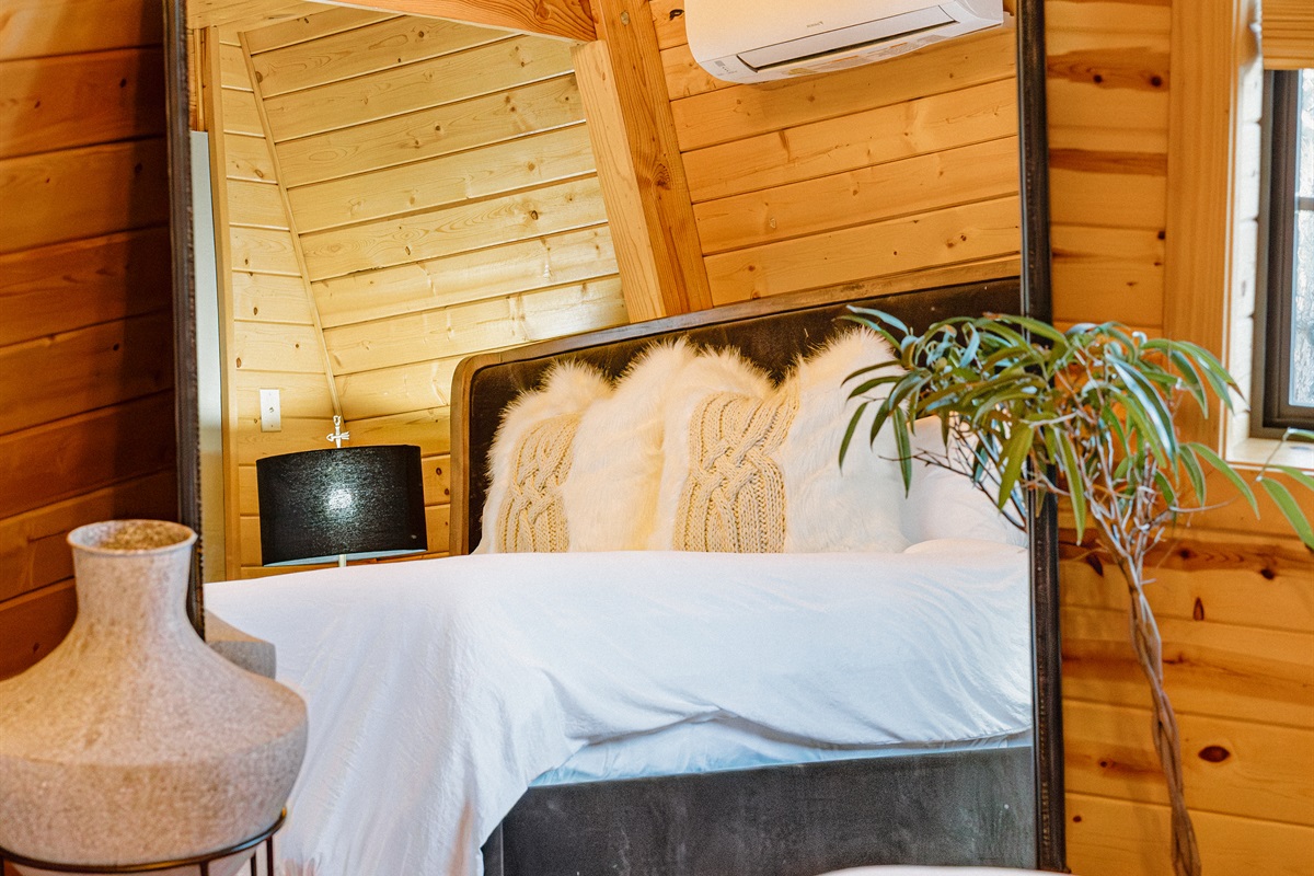 The iconic Anthropologie mirror adds gothic elegance to the bedroom at Poppywood Pines. This stylish Show Low A-frame features curated decor and plush bedding, creating a cozy retreat after exploring White Mountains hiking trails, fishing, and skiing.