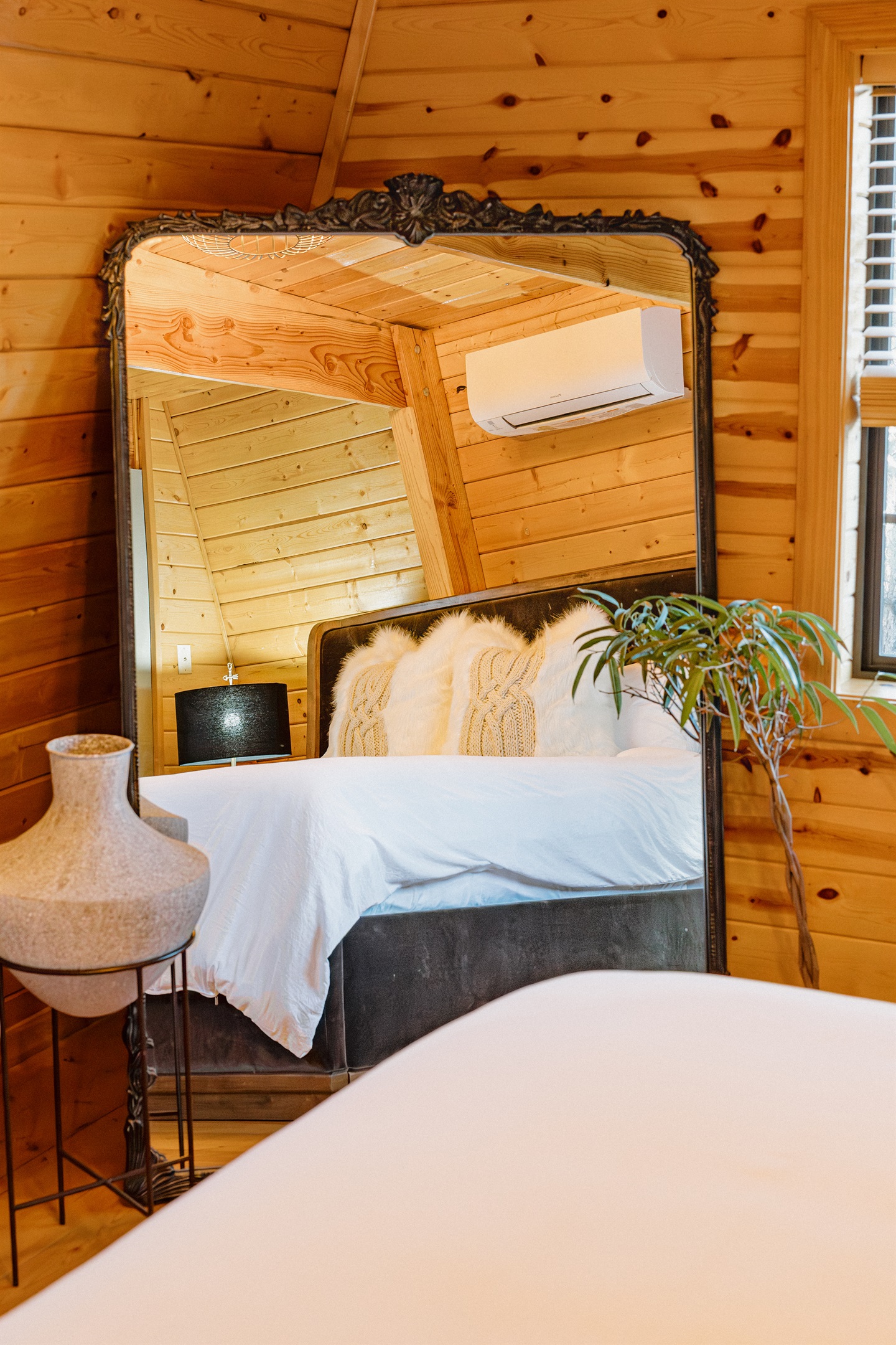The iconic Anthropologie mirror adds gothic elegance to the bedroom at Poppywood Pines. This stylish Show Low A-frame features curated decor and plush bedding, creating a cozy retreat after exploring White Mountains hiking trails, fishing, and skiing.