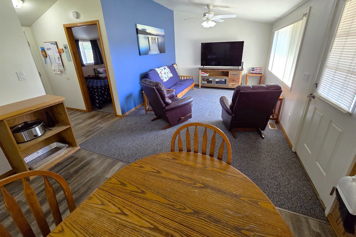The living room features a large picture window, access to the back deck looking towards the swimming pool, play area, horseshoe pits, and Table Rock Lake.