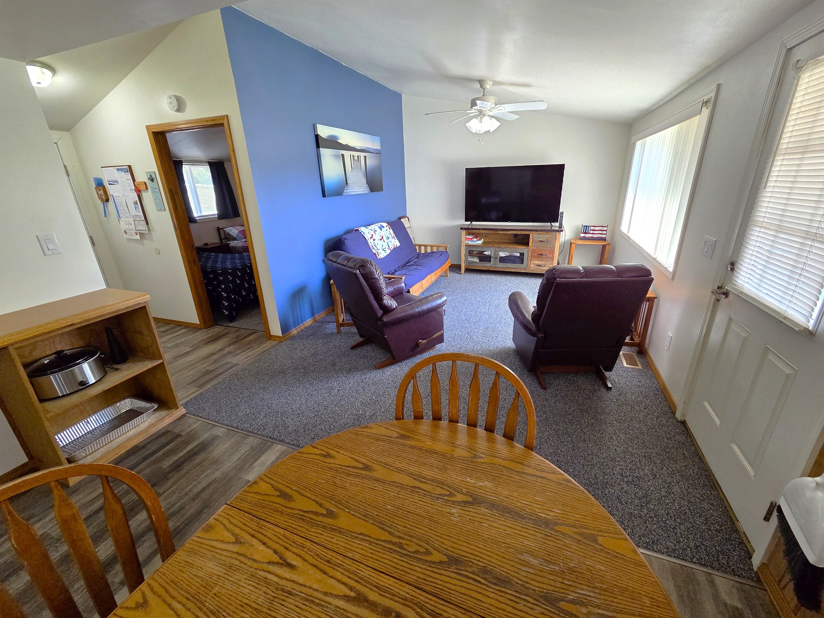 The living room features a large picture window, access to the back deck looking towards the swimming pool, play area, horseshoe pits, and Table Rock Lake.