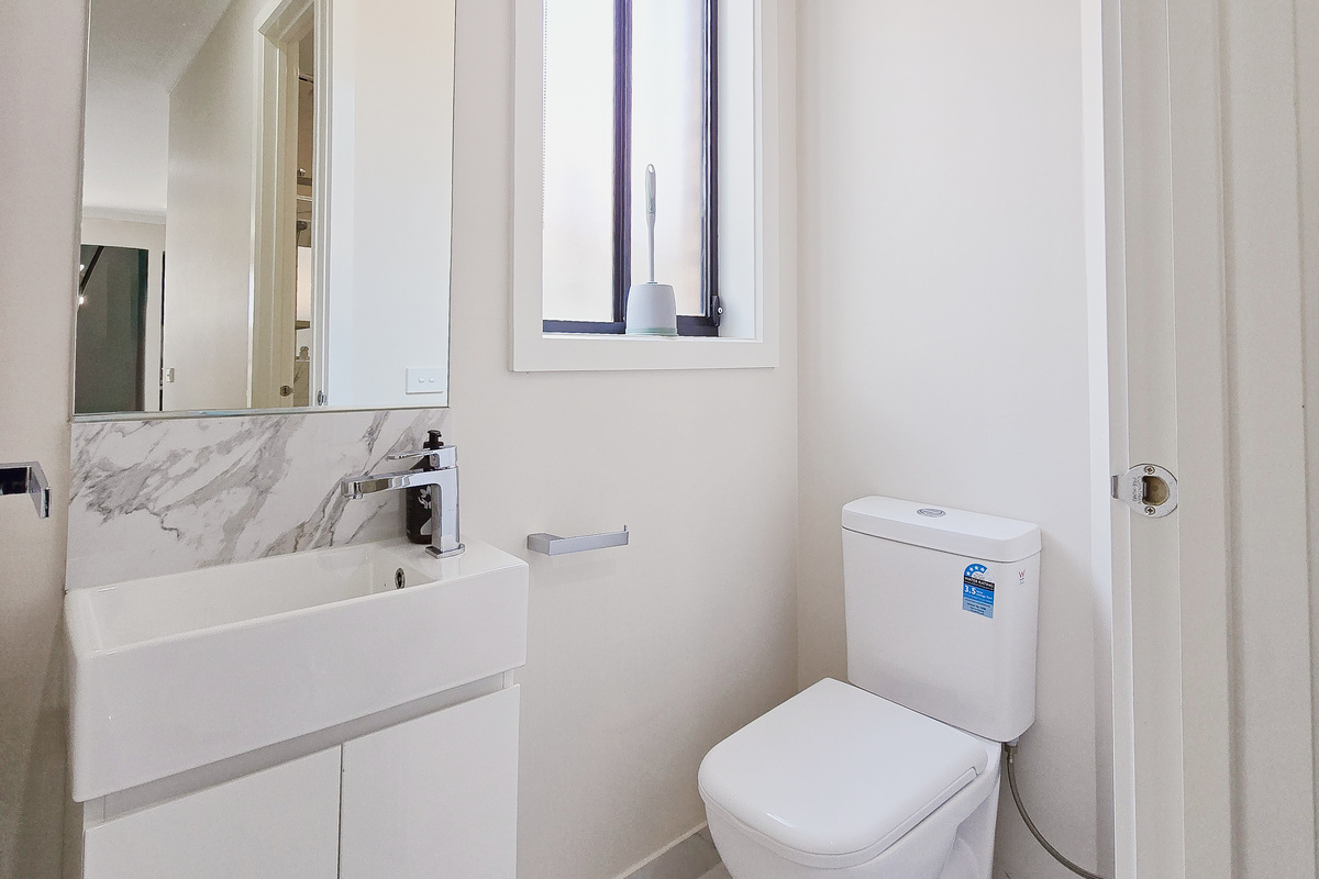 Powder room with toilet, vanity, mirror and window.