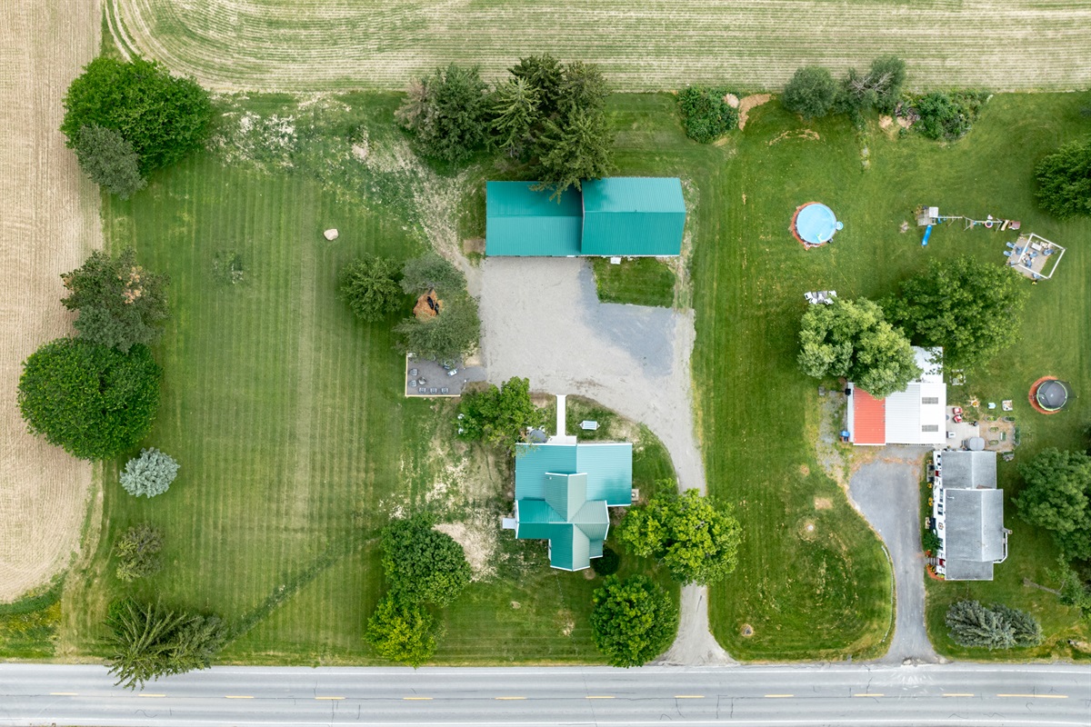 Bird’s-eye view of a well-maintained rural retreat with a long driveway, expansive lawn, and plenty of privacy from neighboring homes.
