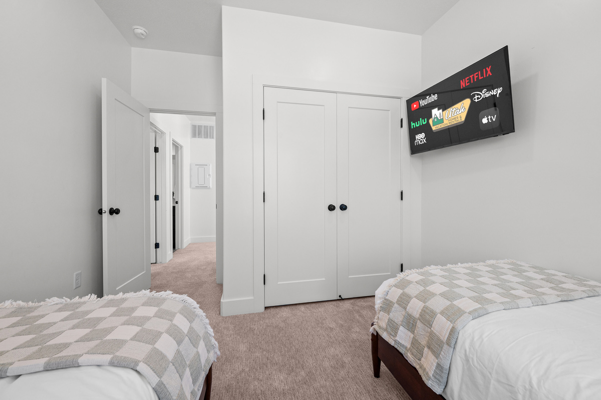 This bedroom offers two beds plus a wall-mounted TV for a comfortable and practical sleeping setup.