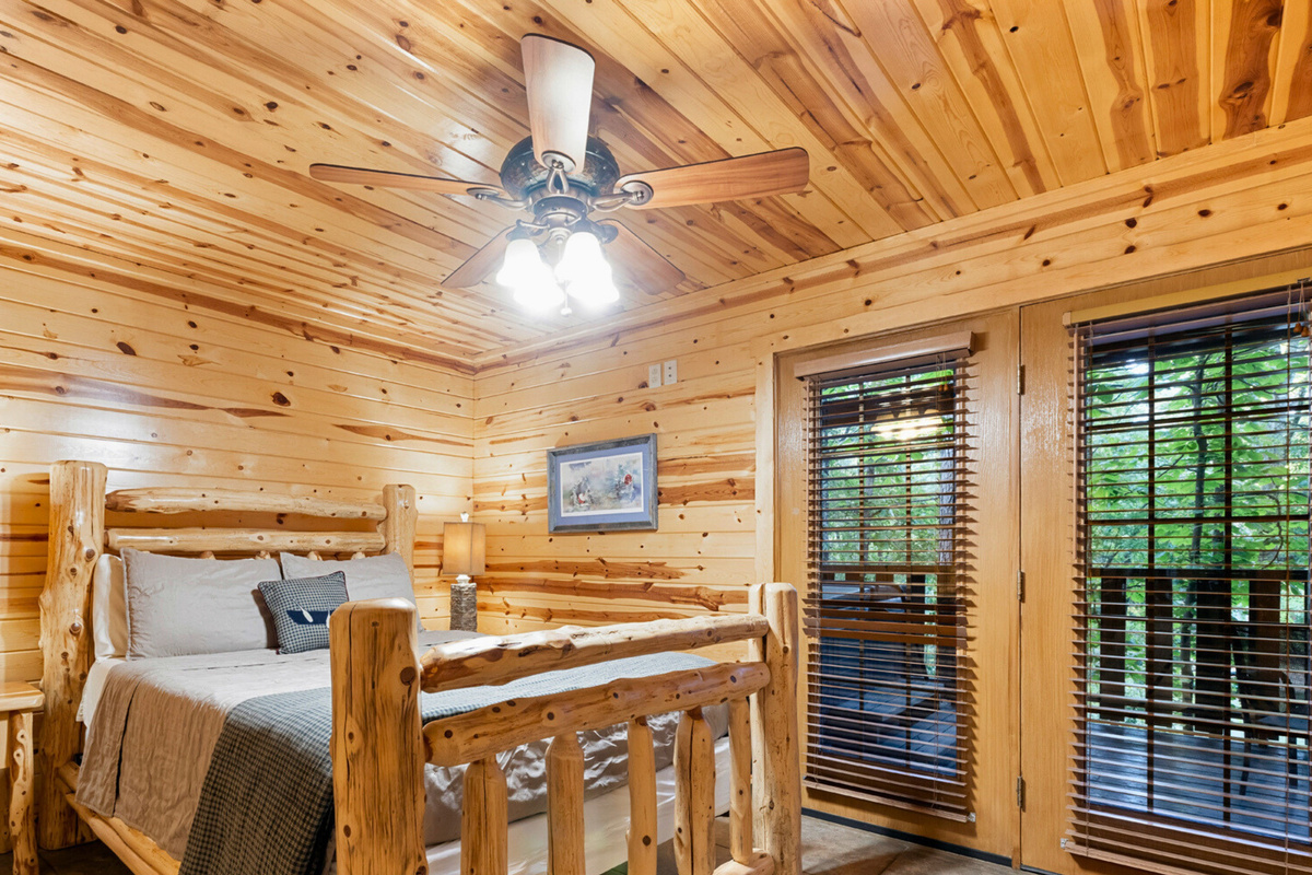 Bedroom 1 with a queen log bed and deck access.