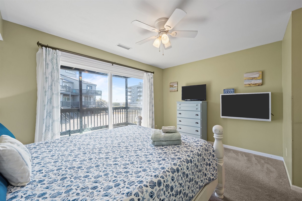 Unwind in a bright queen bedroom with balcony views and a TV for winding down after a full day at the beach