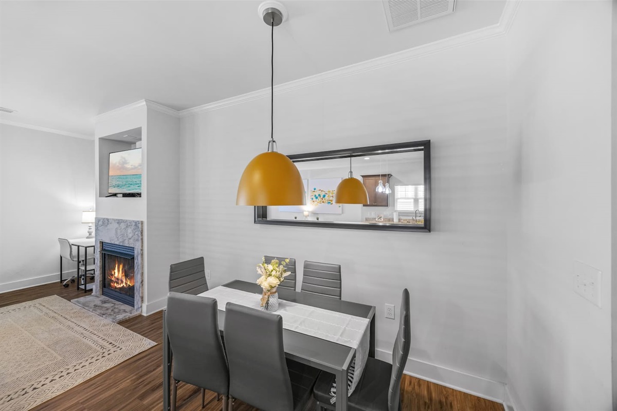 Gather around the modern dining table with seating for six, accented by a bold pendant light and cozy fireplace views.