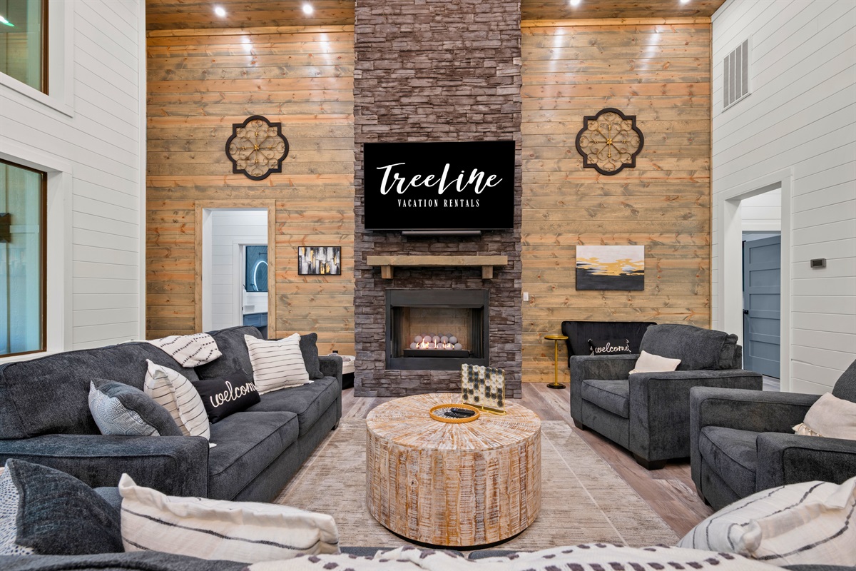 Plush sofas are arranged around the fireplace and TV, creating a cozy space where guests can relax, watch a movie, or simply enjoy time together.