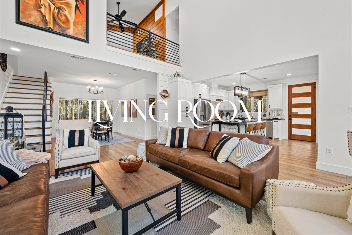 Stepping inside, the living room feels open and inviting with high ceilings, natural light, and comfortable seating.