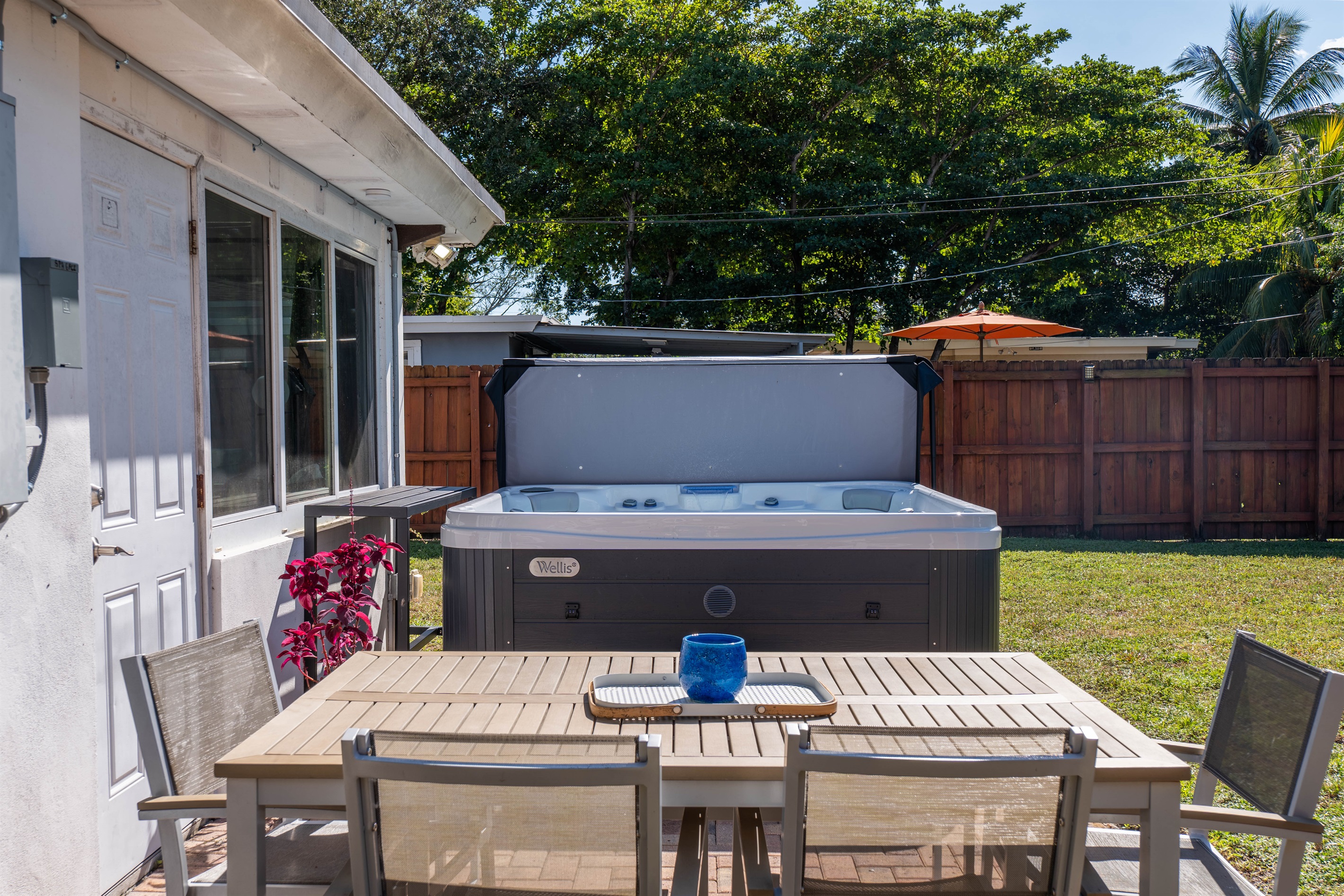 Private fenced backyard with outdoor dining table placed beside the hot tub on the patio