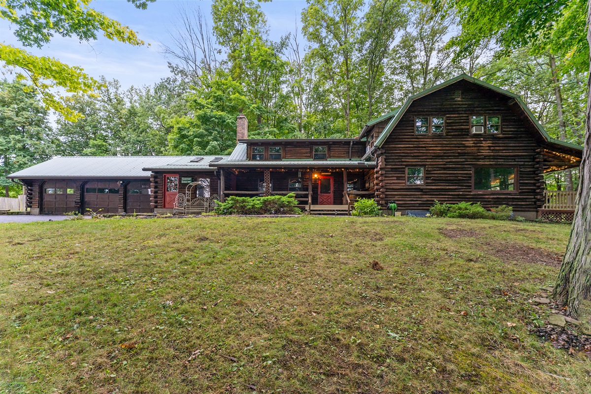 Charming log cabin retreat with rustic details, inviting front porch, and serene wooded surroundings—ideal for a cozy getaway.