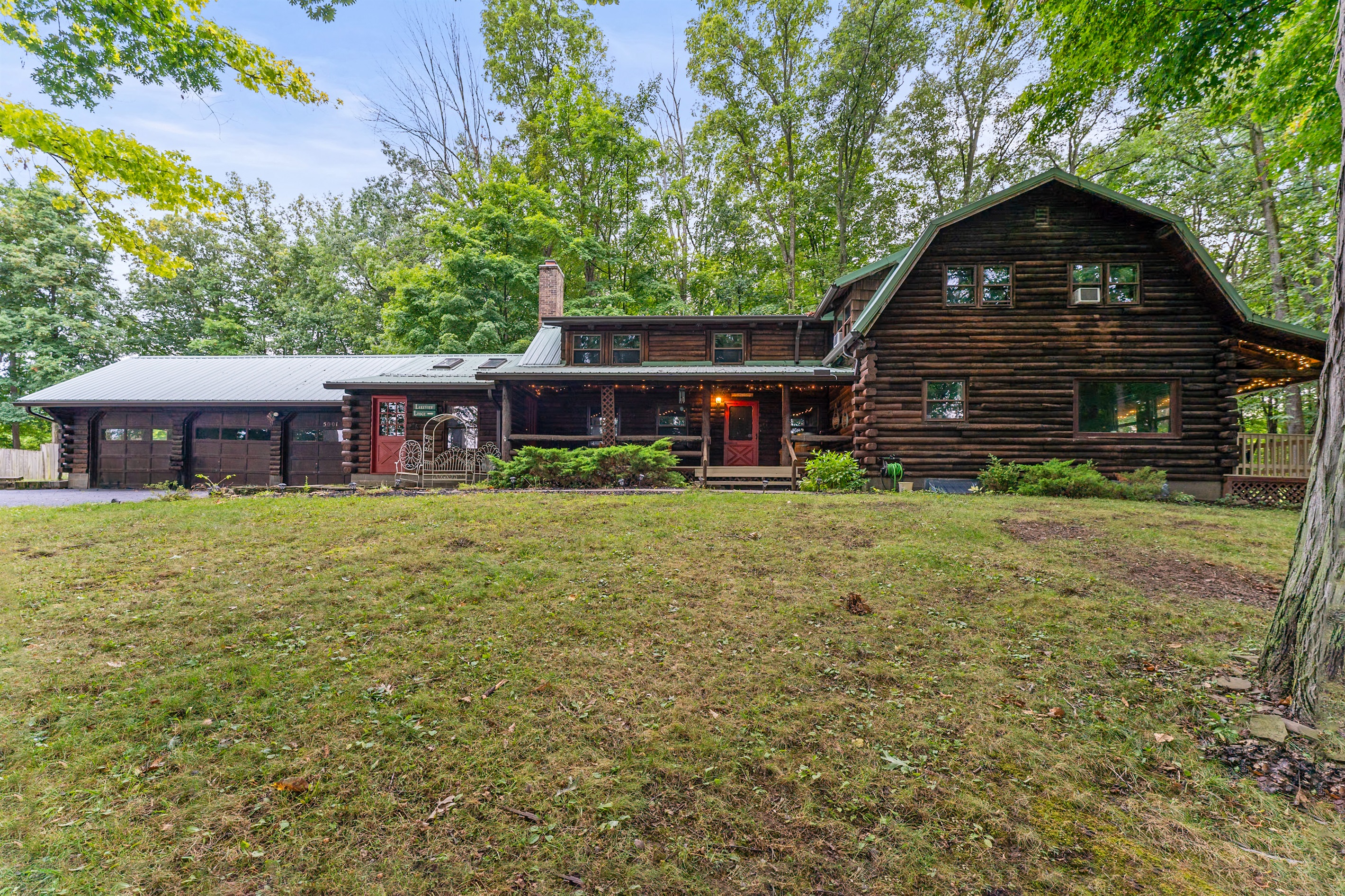 Charming log cabin retreat with rustic details, inviting front porch, and serene wooded surroundings—ideal for a cozy getaway.