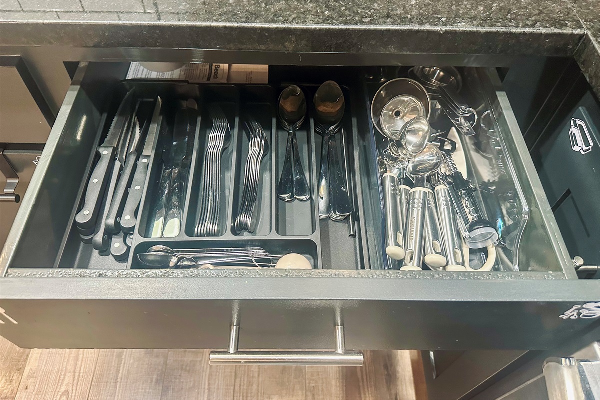 Kitchen drawer stocked with silverware, measuring cups and spoons, and essential cooking utensils for everyday convenience.