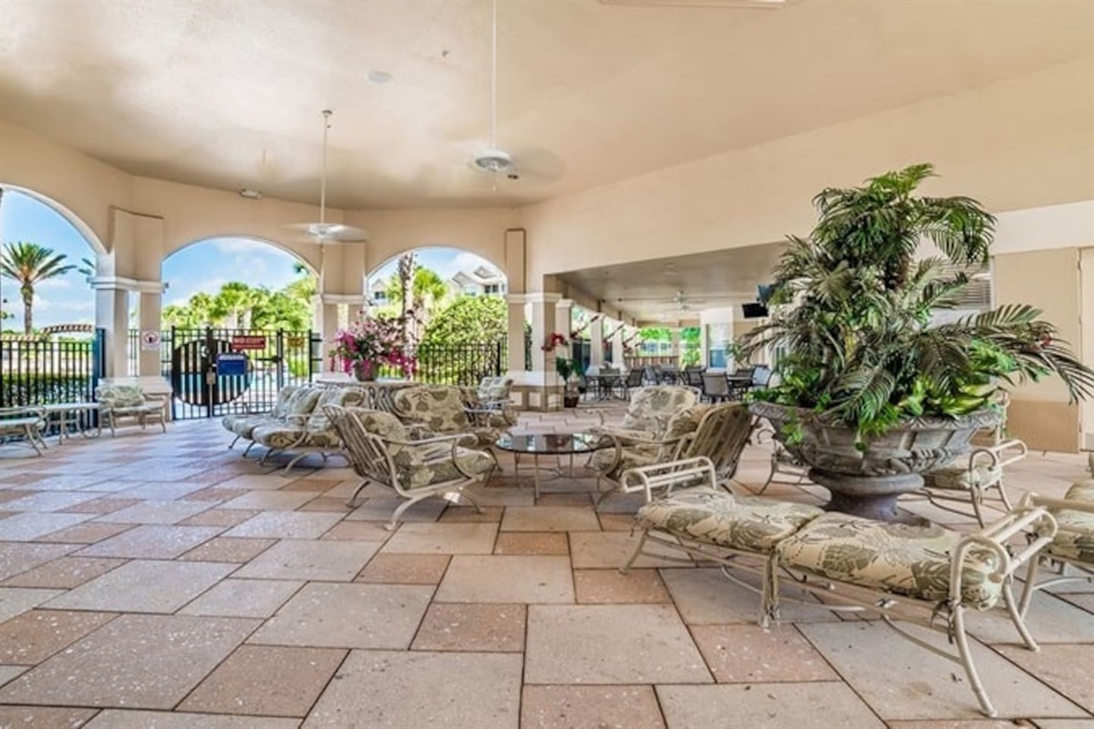 Covered patio with cushioned seating and garden views.

