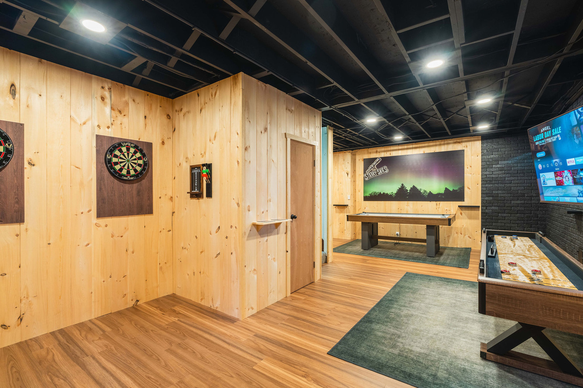 🎯 The Game Lounge: dual dart boards, shuffleboard, air hockey, foosball and a 65" HDTV under a Northern Lights theme.