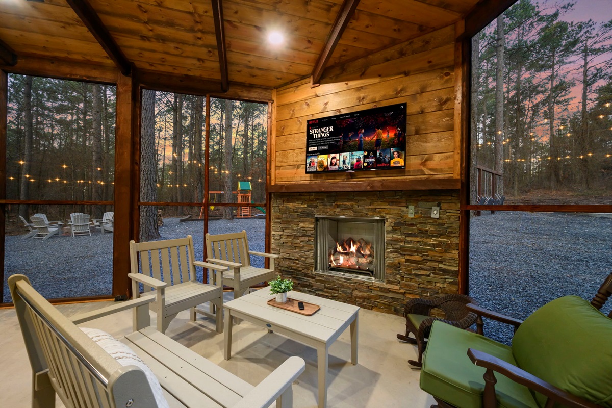 Screened-in porch with cozy seating, fireplace, and TV &mdash; perfect for year-round outdoor lounging.