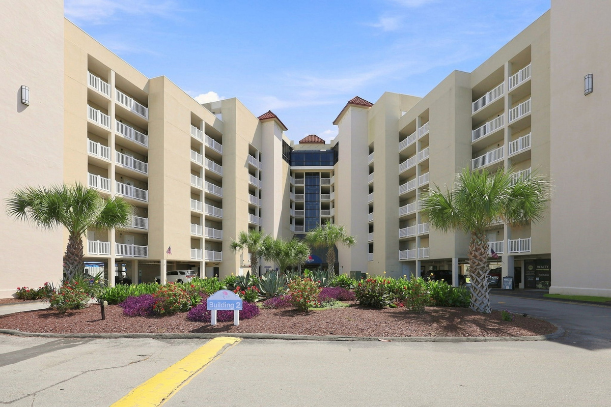 Front facade and entrance drive of the resort property, framed by tropical landscaping and classic coastal architecture.