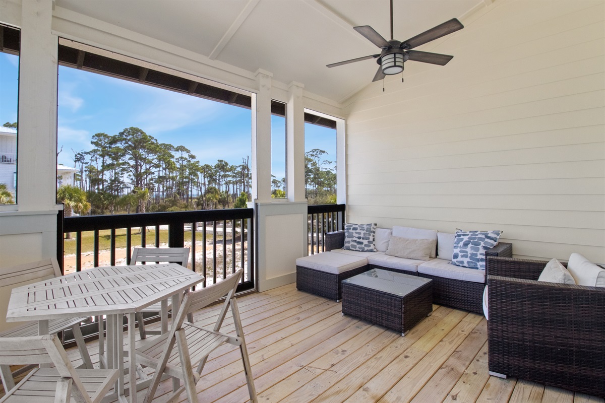 Large screen porch off kitchen has outdoor seating + dining