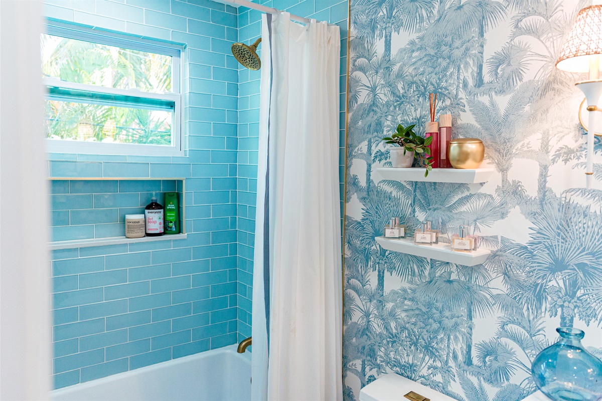The cottage bathroom exudes palms and ocean in shades of blue and green.