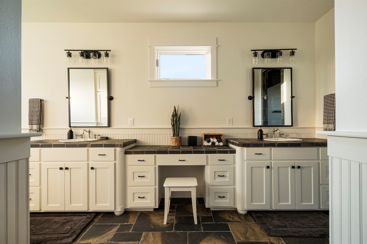 A spacious and elegantly designed bathroom featuring a double vanity with ample storage, a dedicated makeup area, and stylish fixtures.
