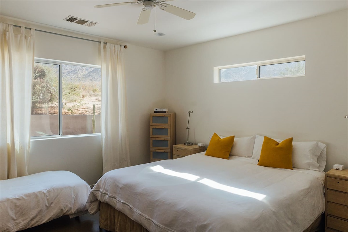 Modern bedroom with queen size bed, additional cot and private bathroom.