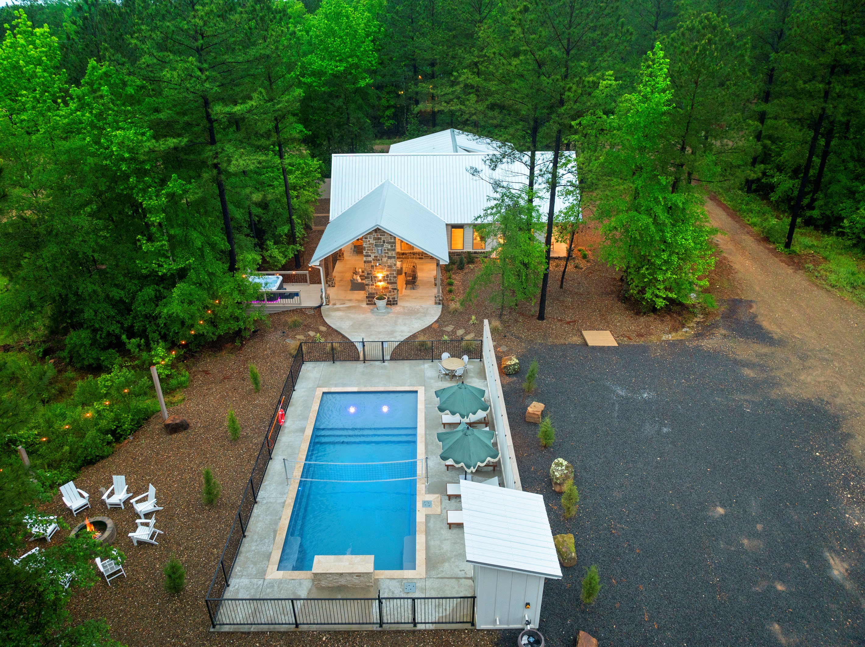 An aerial look at the heart of the property: the pool, covered patio, hot tub, & firepit create the perfect setting for a memorable stay with parking conveniently located to the right. Not pictured: Kids playset and fenced yard for dogs!