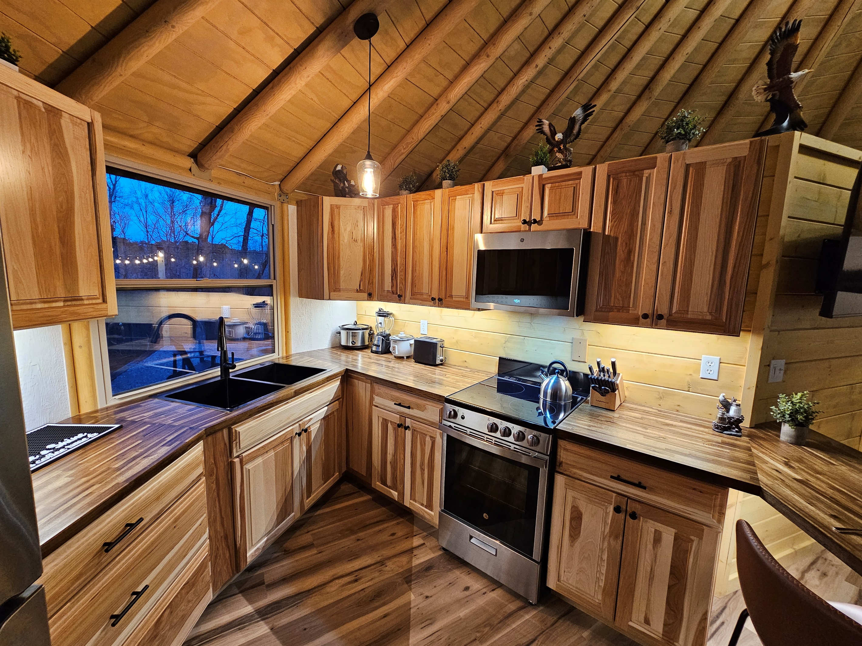Warm, fully equipped kitchen at Eagle Retreat featuring custom wood cabinetry, full-size stove and oven, microwave, dishwasher, and modern farmhouse sink—perfect for cooking meals after a day