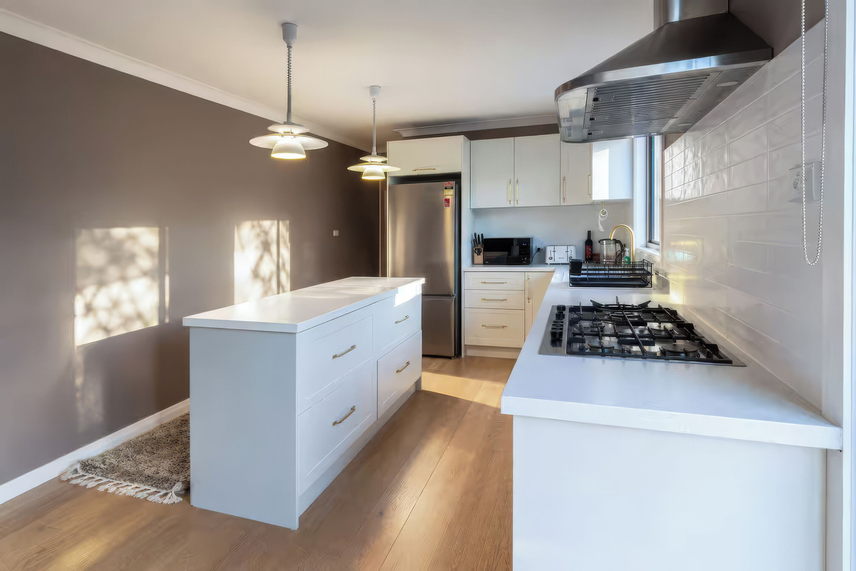 Enjoy a spacious upstairs kitchen with an island bench, complete with everything needed for cooking and dining. A first aid kit is available in the cupboard above the fridge.