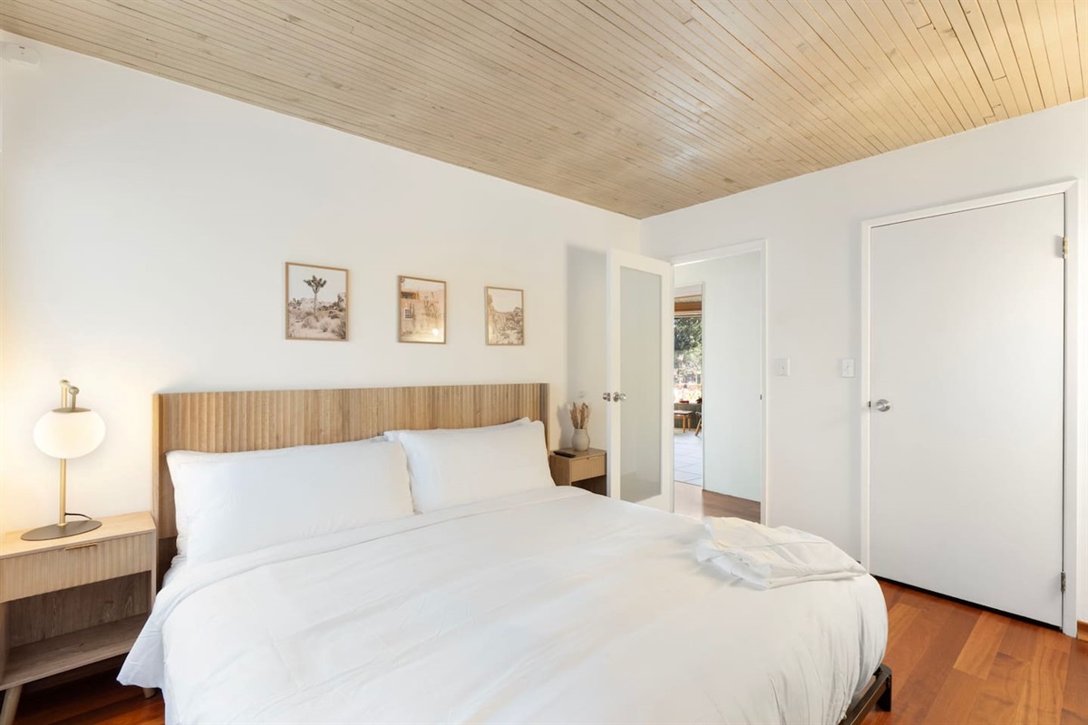 Bright and airy bedroom with a cozy queen bed, warm wood accents, and soft lighting for a comfortable and relaxing stay.