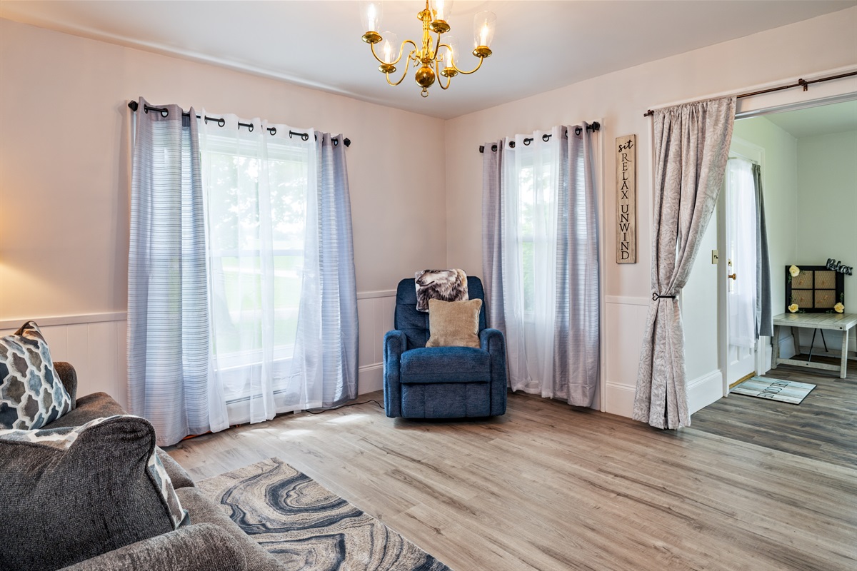 Bright and inviting living room featuring a cozy recliner, soft natural light, and charming farmhouse-style décor—perfect for relaxing after a day exploring the Finger Lakes
