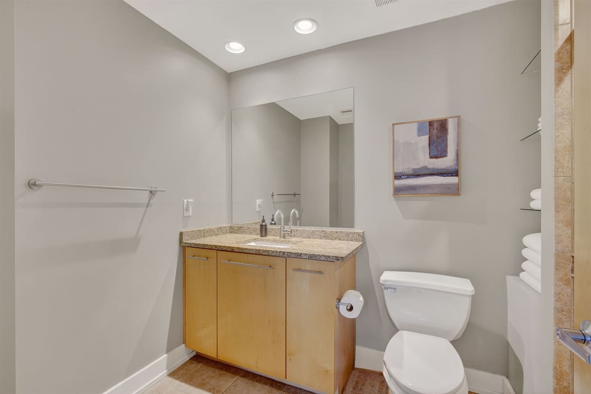 Modern bathroom with granite vanity, oversized mirror, and sleek fixtures. Stocked with essentials and fluffy towels, this stylish space makes freshening up easy and convenient during your Des Moines stay.