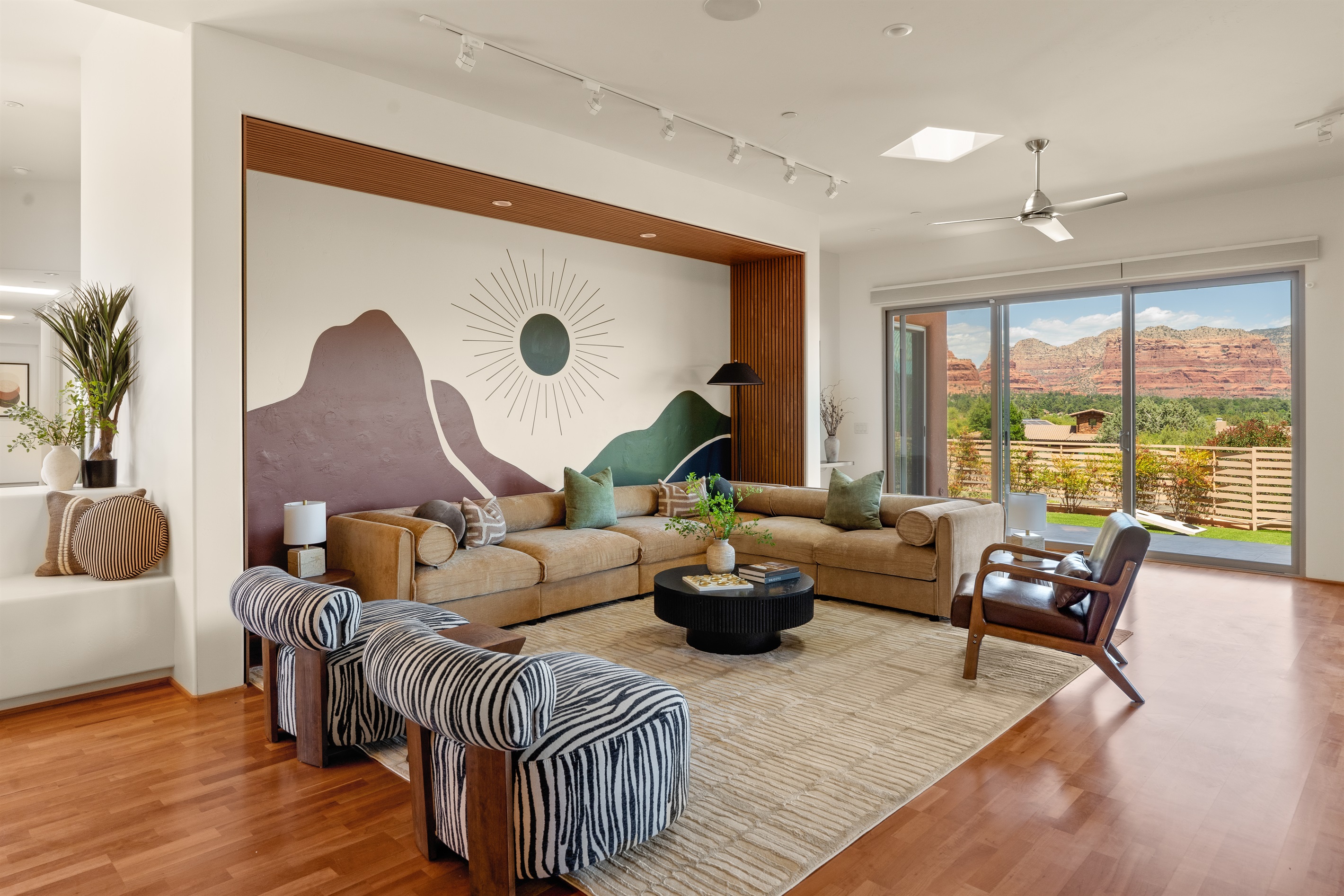 Step into luxury. The main living space at Elara Retreats offers expansive seating, a striking custom mural, and panoramic windows that bring the Sedona landscape indoors.