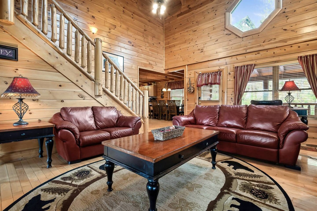 Living room with front door and kitchen in the background.Larger couch contains a pull out sofa bed.