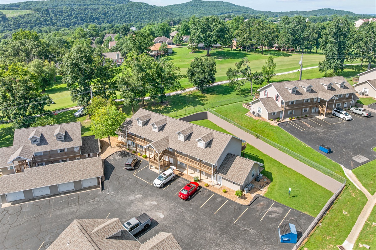 Aerial view of the building set among greenery and neighboring fairways.
