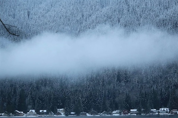 Winter landscape with fog and snow-dusted hills.